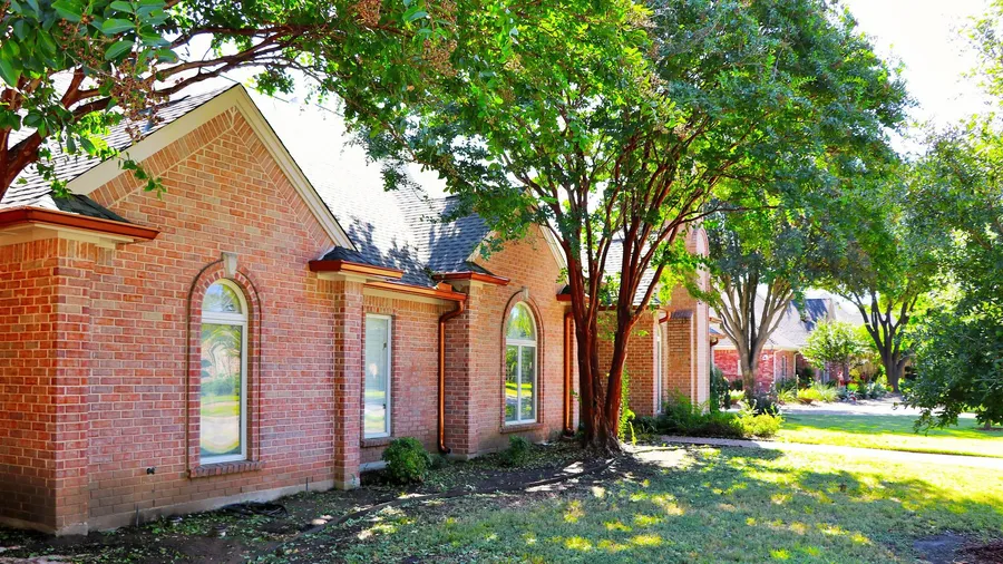 A red brick home with copper-tone gutters and downspouts