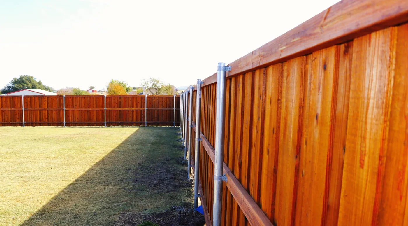 A cedar board fence on steel posts running along a lawn