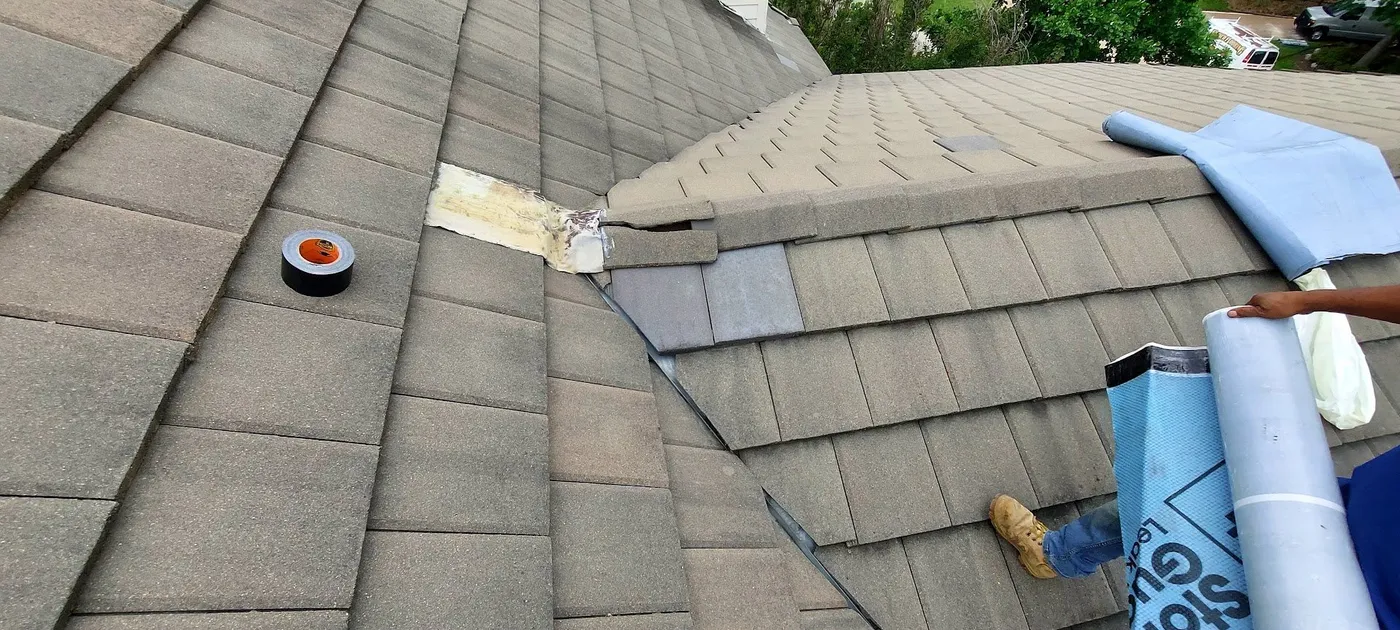 A concrete tile roof opened for repair, with new underlayment going down