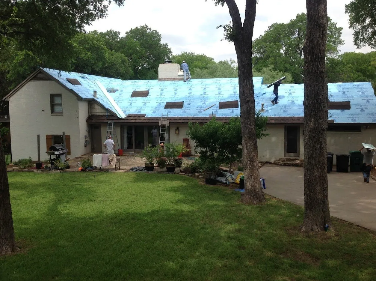 A one-story home mid re-roof, covered in blue synthetic underlayment