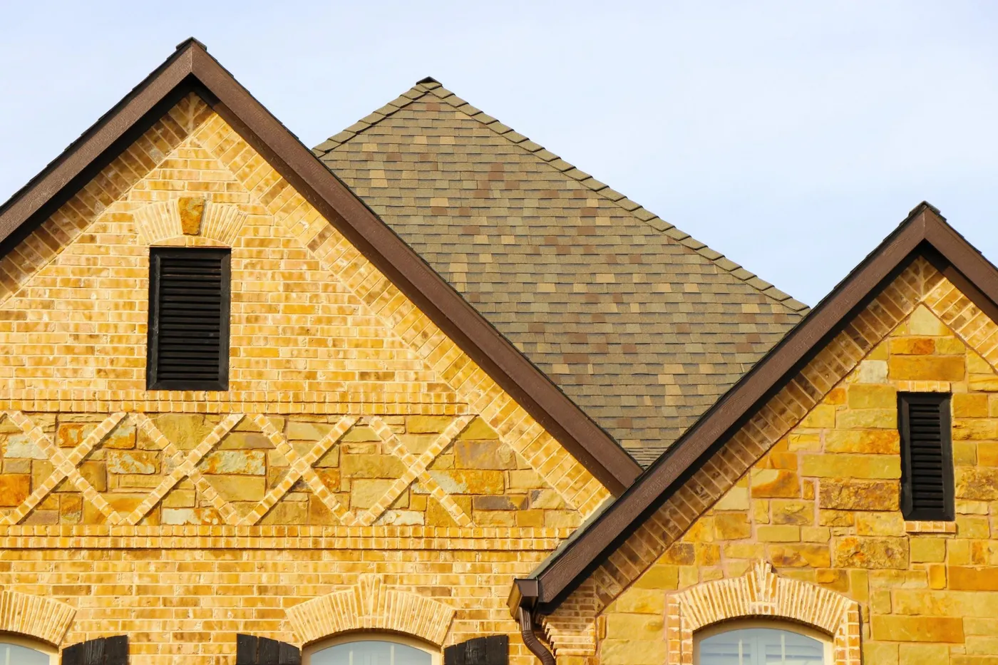 Stone and brick gables under a tan architectural shingle roof
