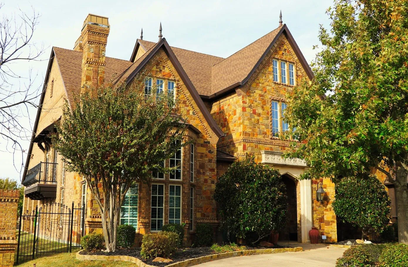 A stone Tudor two-story with a tall chimney and a brown shingle roof